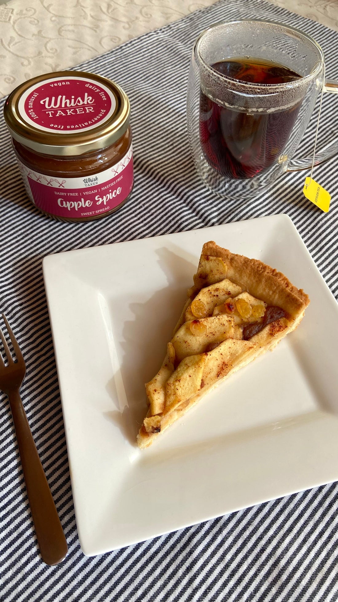 A warm apple pie on a rustic wooden table, featuring golden-brown crust and spiced apple filling made with Whisktaker's Apple Spice Spread