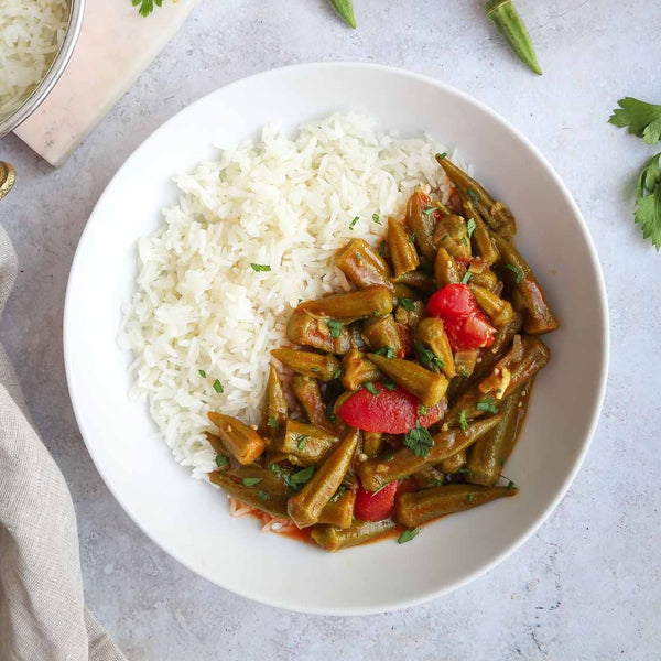 A bowl of Lebanese bamya bemyeh stew made with tender okra and tomatoes served alongside white rice.