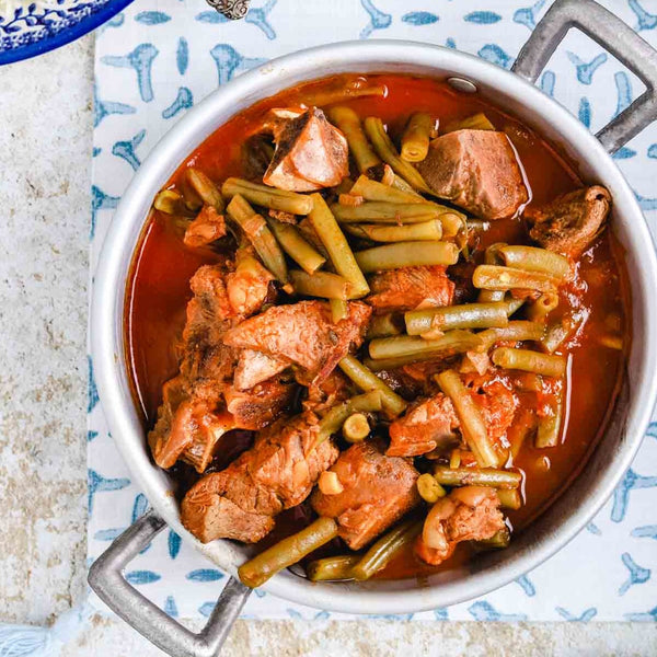 A pot of Lebanese green bean stew cooked in a rich tomato sauce with tender beef pieces.