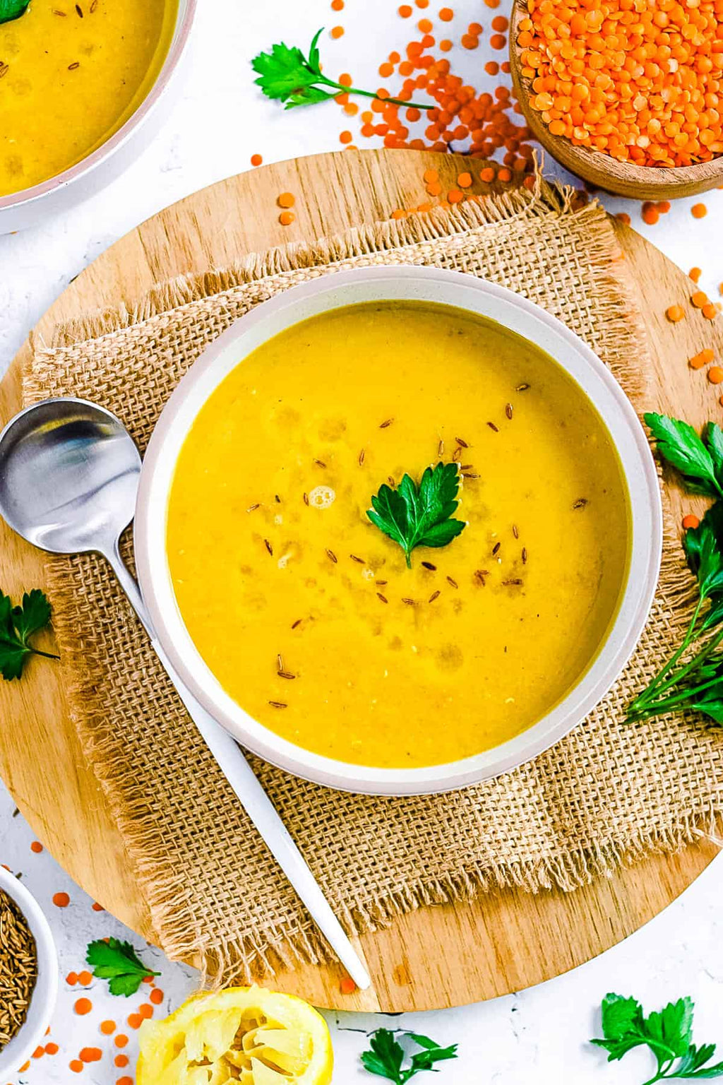 Yellow soup in a white bowl on a wooden board with lentils and parsley. Whisktaker Lentil Soup Lebanon Healthy Food